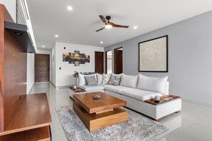 Ein modernes Wohnzimmer mit einem weißen Sofa, einem Holztisch und einem Deckenventilator.