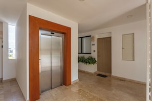 A hallway with a modern elevator, a door labeled '602', and a potted plant. - Studio in a prime location, just a few meters from 5th Street and the beach (Playa del Carmen)
