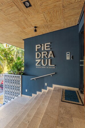 A building entrance with a sign reading 'PIEDRA ZUL DOWNTOWN STUDIOS' and a staircase leading up.