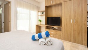 Una habitación de hotel con una cama, televisión, armarios de madera y una ventana con cortinas.