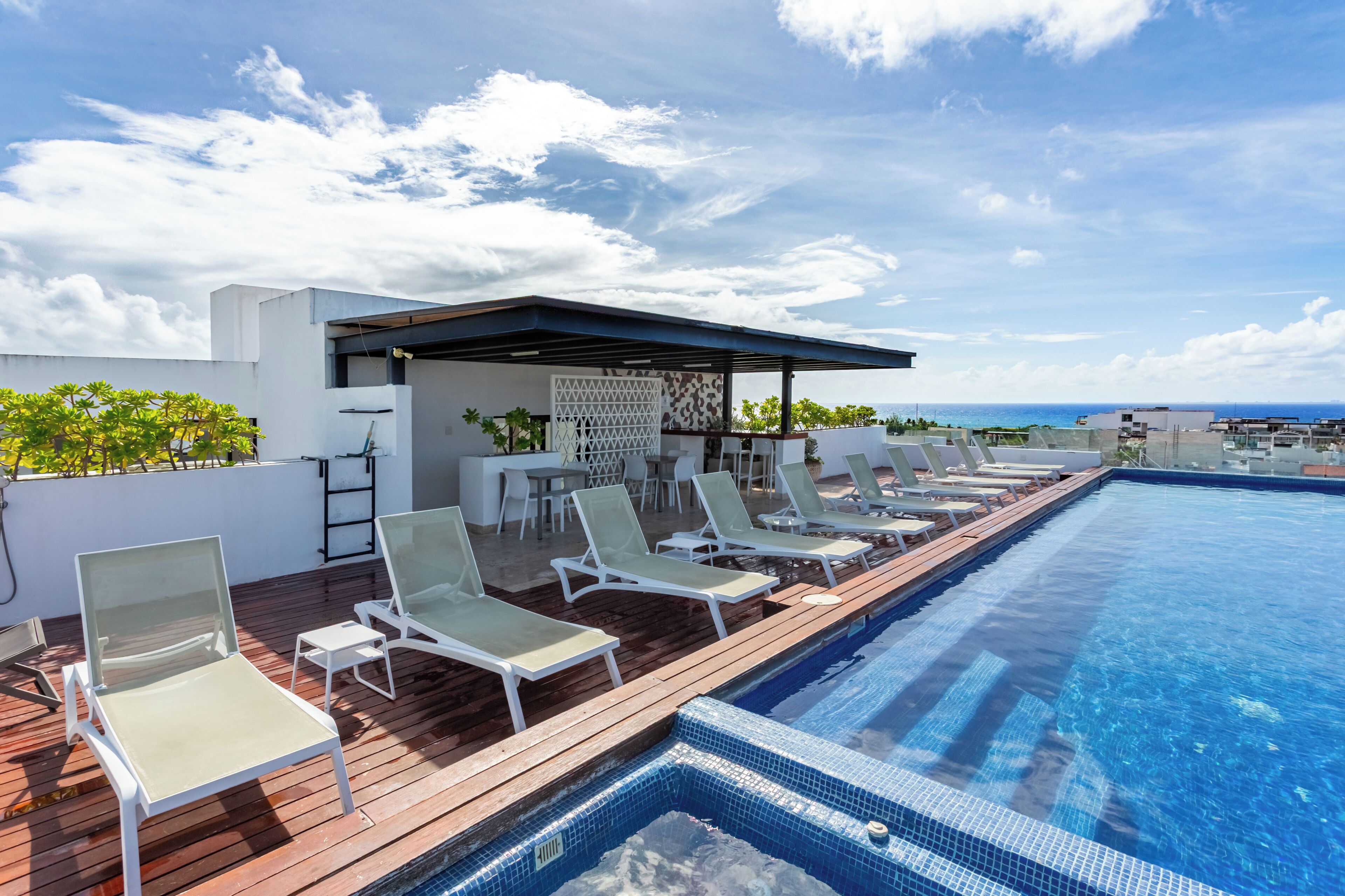 A rooftop pool with lounge chairs and a covered seating area.