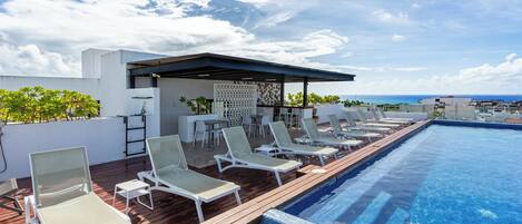 A rooftop pool with lounge chairs and a covered seating area.