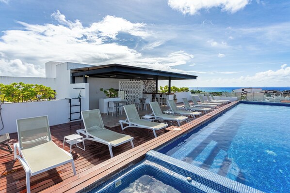A rooftop pool with lounge chairs and a covered seating area.