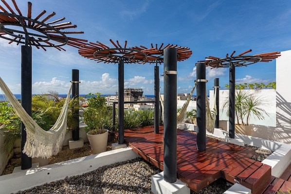 A rooftop terrace with a hammock, potted plants, and a view of the city. - Studio in a prime location, just a few meters from 5th Street and the beach (Playa del Carmen)