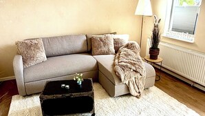 Una sala de estar con un sofá, una mesita, una lámpara y un radiador.