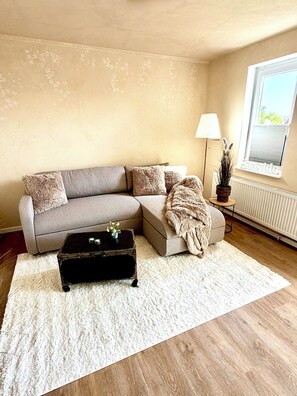 A living room with a sofa, a small table, a lamp, and a radiator.