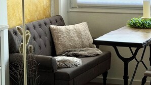 Una habitación con un sofá gris, una lámpara de pie, una mesa con una vela y vistas al mar a través de una ventana.