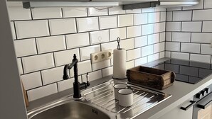 Una cocina moderna con armarios blancos, un lavamanos de acero inoxidable, una tabla de cortar de madera y un horno empotrado.