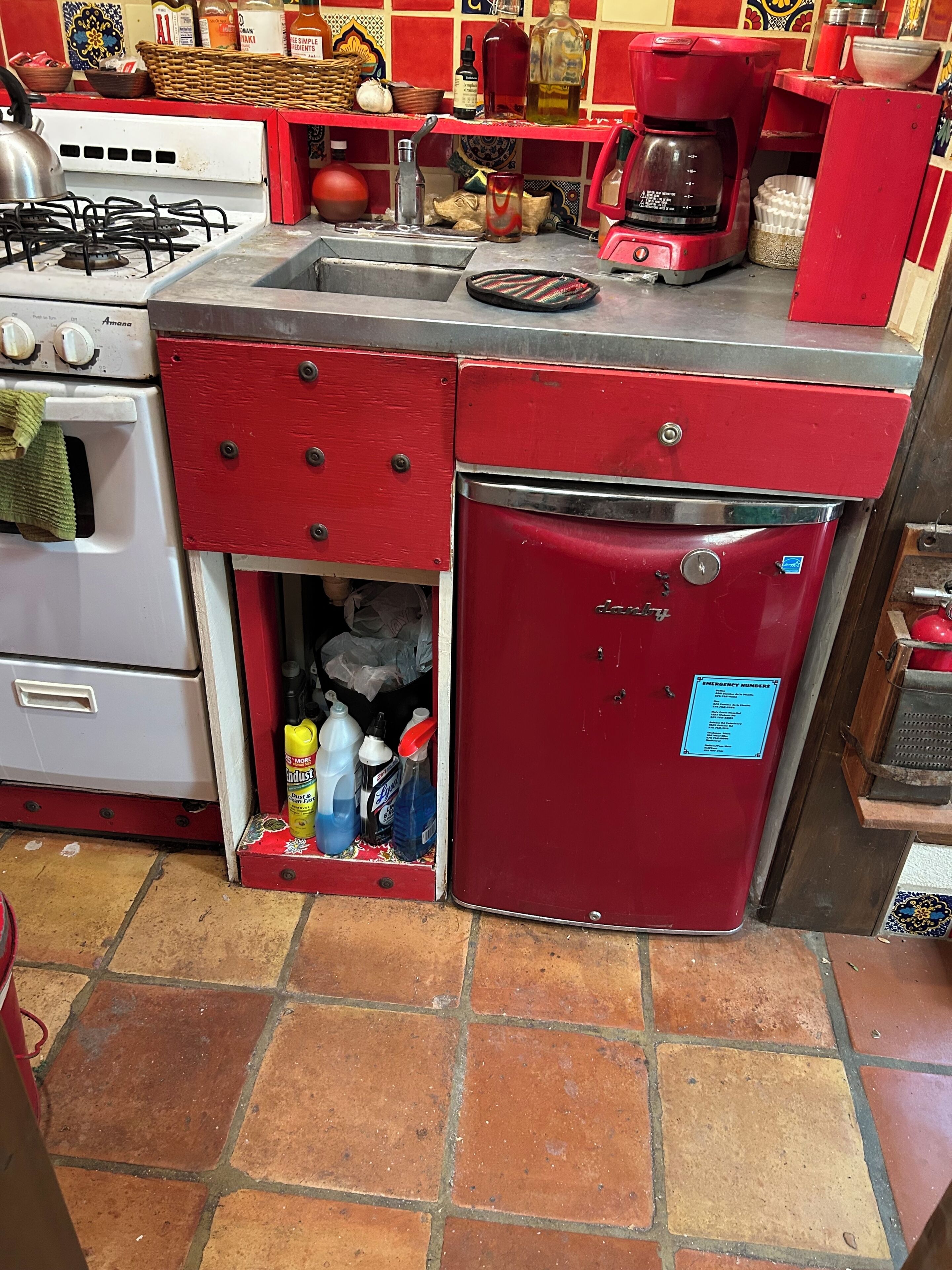 Una cocina con un refrigerador rojo, una estufa y diversos utensilios de cocina.