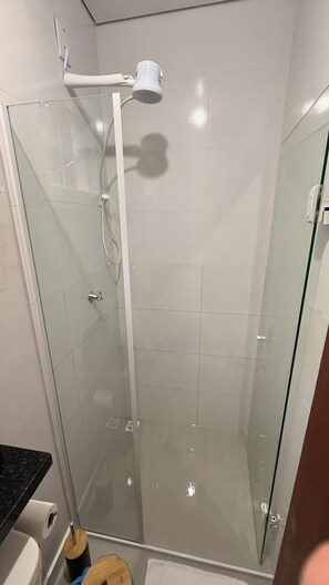 A glass-enclosed shower stall with a handheld showerhead, a glass door, and a visible towel rack. - LOFT127 - 02 (Itajaí)