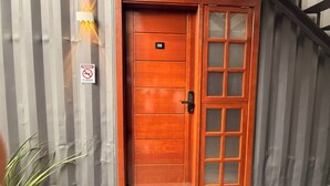 A wooden door with a number plate, a no-smoking sign, and a vertical striped wall. - LOFT127 - 02 (Itajaí)