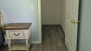 A room with a wooden floor, a white door, and a small white table with drawers. - Entire Home in Dover, DE/Close to Raceway/Casino (Dover)