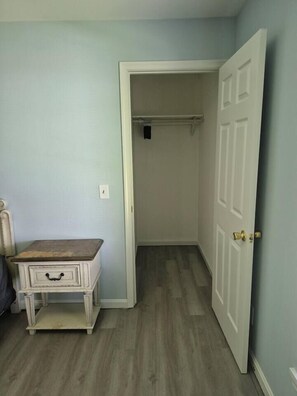 A room with a wooden floor, a white door, and a small white table with drawers. - Entire Home in Dover, DE/Close to Raceway/Casino (Dover)