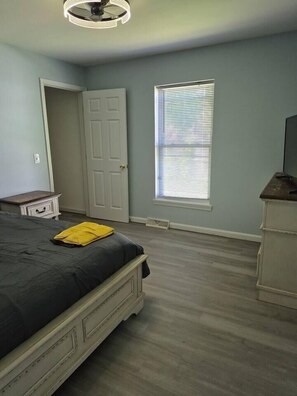 A bedroom with a bed, a dresser, a window with blinds, and a door. - Entire Home in Dover, DE/Close to Raceway/Casino (Dover)