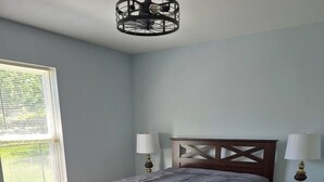 A bedroom with a bed, two bedside lamps, a wooden headboard, a window with blinds, and a wooden dresser. - Entire Home in Dover, DE/Close to Raceway/Casino (Dover)