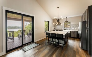 A modern kitchen with a large island, black cabinets, and a view of a lake. - Oak Ridge on Beaver Lake, 5BR Lakeview, Sleeps 13 (Garfield)
