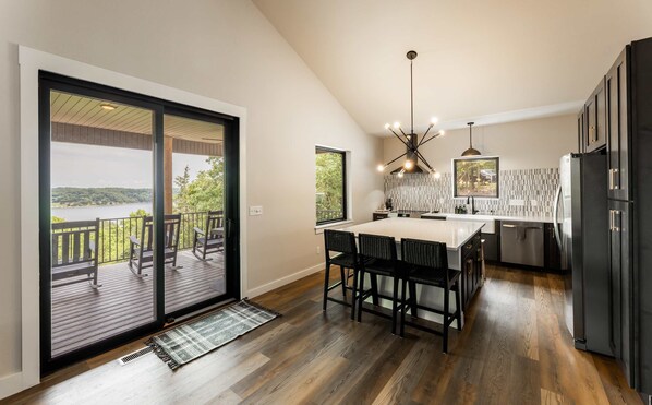 A modern kitchen with a large island, black cabinets, and a view of a lake. - Oak Ridge on Beaver Lake, 5BR Lakeview, Sleeps 13 (Garfield)