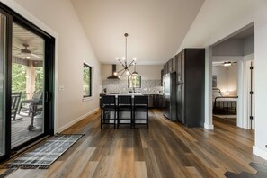 A modern kitchen with a central island, dark cabinetry, and a large refrigerator. - Oak Ridge on Beaver Lake, 5BR Lakeview, Sleeps 13 (Garfield)