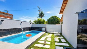 A swimming pool with a clear blue water, surrounded by a white wall and a tiled deck. - Refúgio Unamar - Cabo Frio RJ (Cabo Frio)