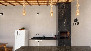 A kitchen with a marble backsplash, a built-in oven, and a hanging light fixture. - Refúgio Unamar - Cabo Frio RJ (Cabo Frio)
