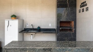 A modern kitchen with a marble countertop, a built-in oven, and pendant lights. - Refúgio Unamar - Cabo Frio RJ (Cabo Frio)