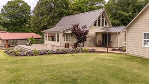 Eine Blockhütte mit einer Terrasse, Sitzgelegenheiten im Freien und einem Garten.