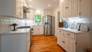 Una cocina moderna con armarios blancos, un refrigerador de acero inoxidable y piso de madera.
