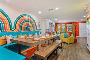A dining area with a long wooden table set for a meal, a sofa, and a bench. - The Rainbow Lagoon - Pickleball, Heated Pool, Golf (Bradenton)