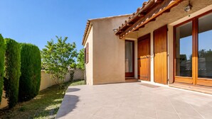 A house with a tiled patio, wooden doors, and a clear sky.