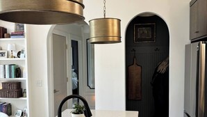 Ett kök med en bänkskiva i marmor, en diskho i rostfritt stål och en hängande lampa.