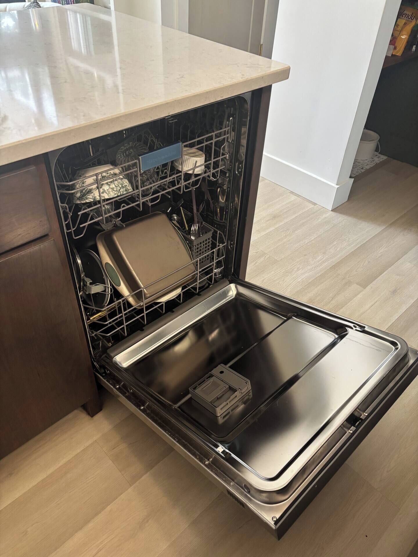 A kitchen with a dishwasher, a countertop, and a wooden cabinet.