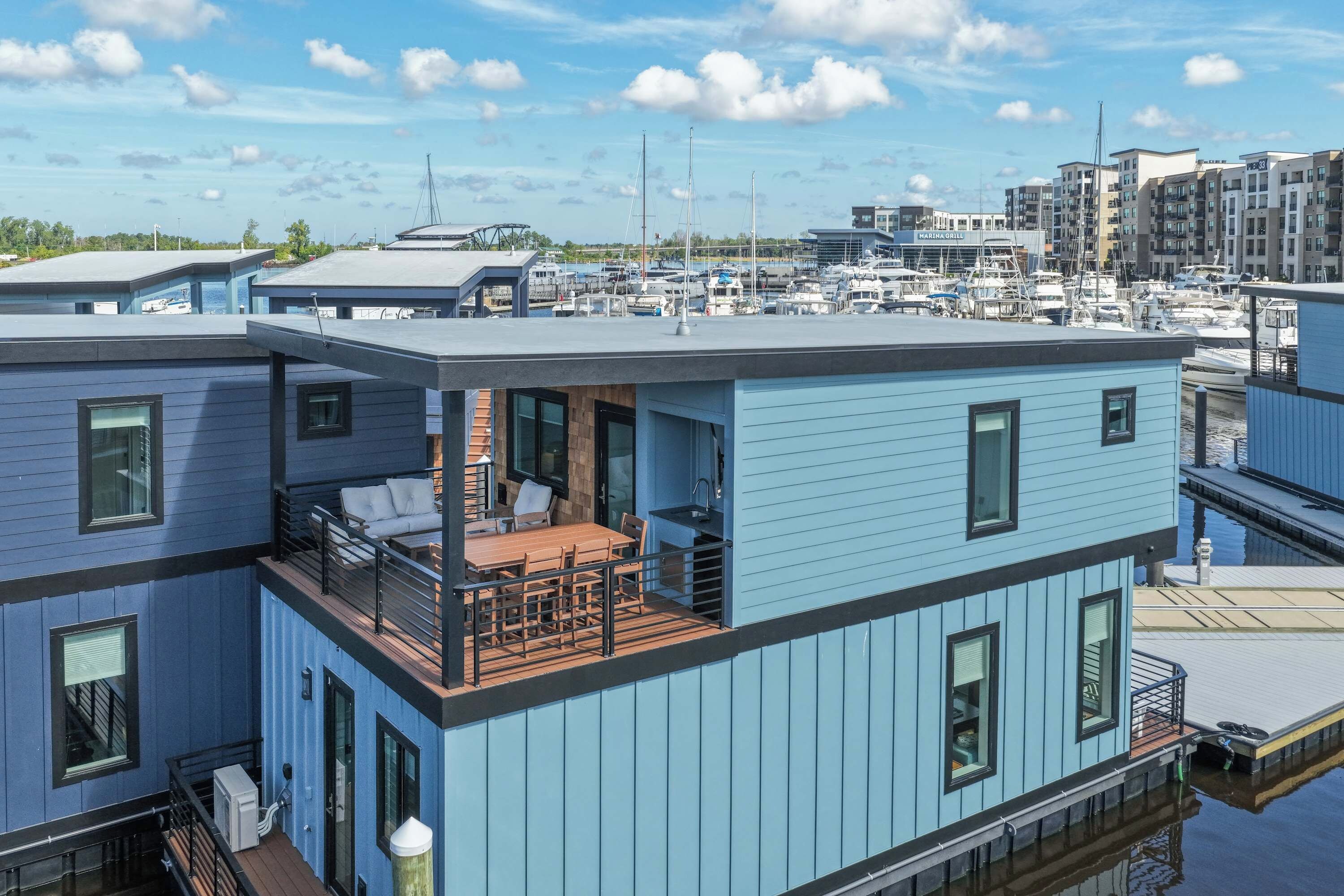 A modern multi-story building with a rooftop deck featuring outdoor furniture.