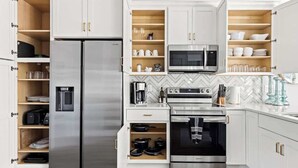 A modern kitchen with a built-in refrigerator, microwave, oven, and coffee maker. - Palm Springs at The Cove Riverwalk Villas (Wilmington)