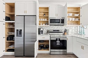 Eine moderne Küche mit Einbaukühlschrank, Mikrowelle, Backofen und Kaffeemaschine.
