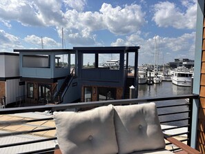 Ein Balkon mit Blick auf eine Marina, eine Treppe und ein Gebäude mit Holzfassade.