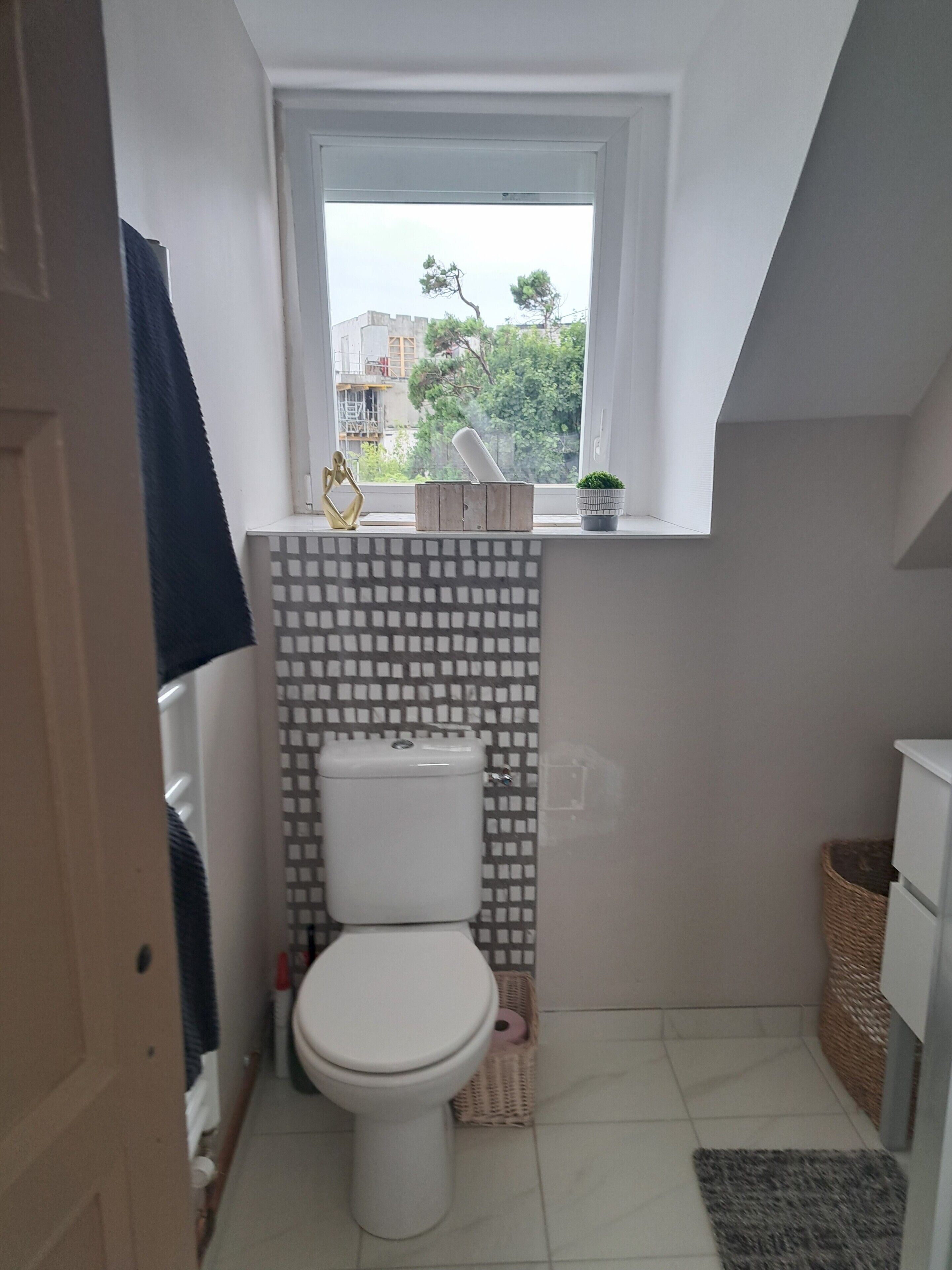 Un baño pequeño con inodoro, ventana y salpicadero de azulejos.