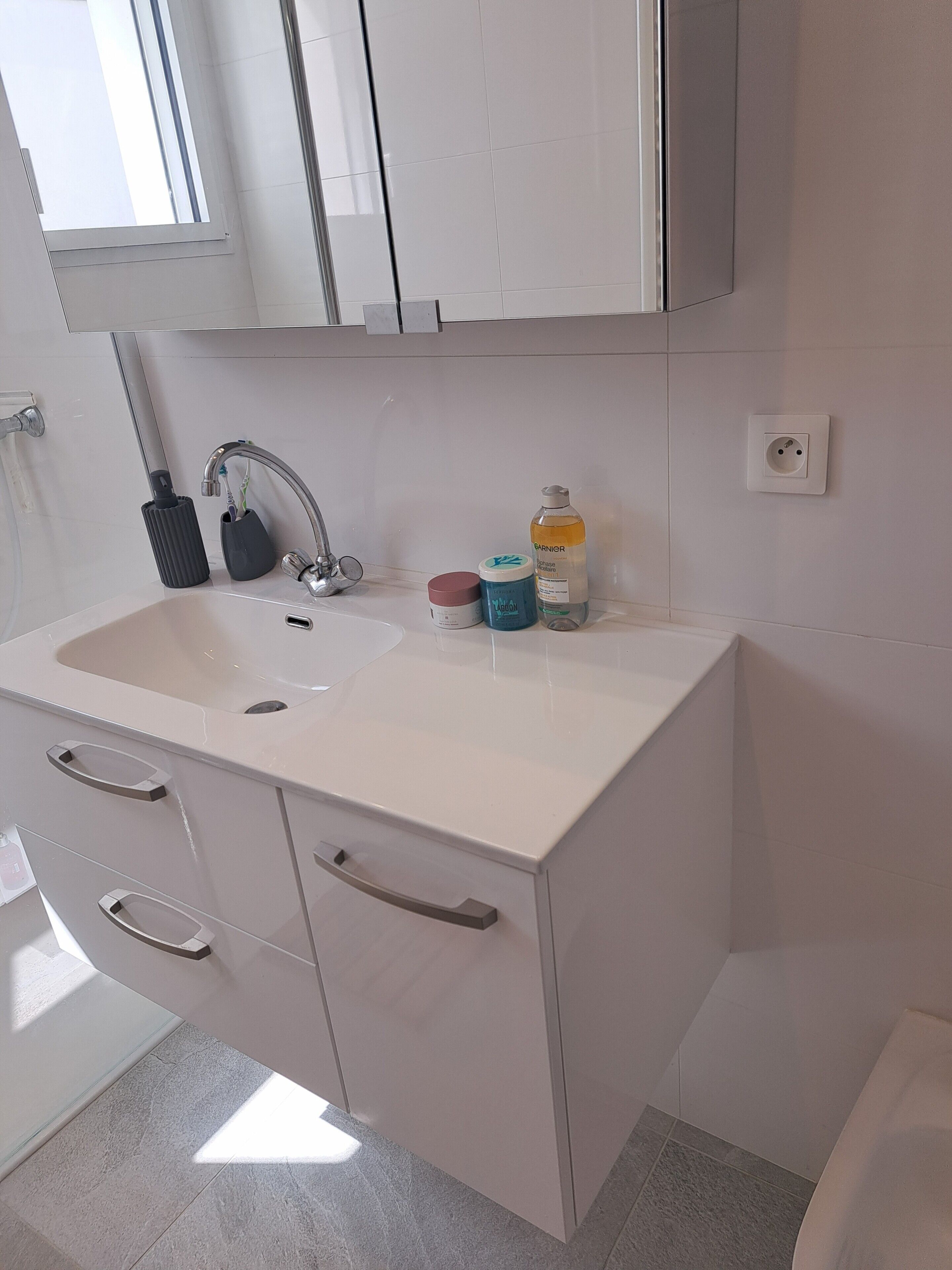A bathroom with a white sink, a mirror, a faucet, and a window.