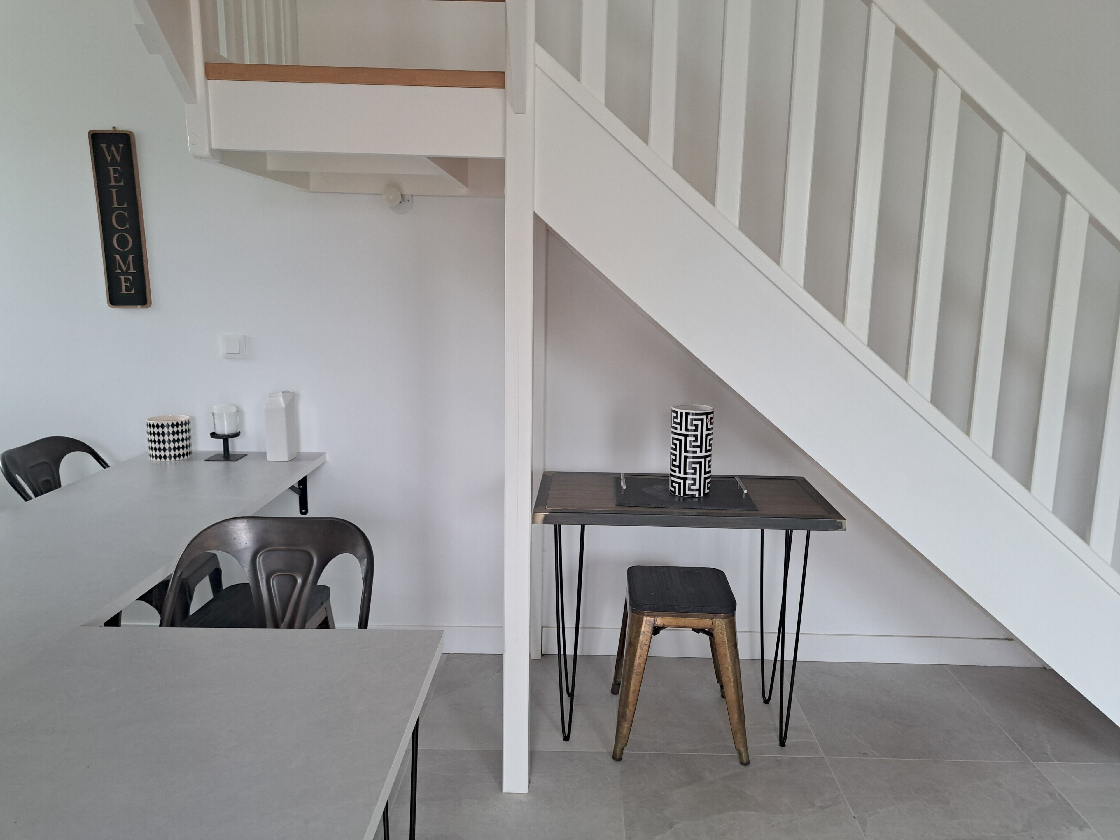 A modern interior with a dining area, a staircase, and a minimalist design.