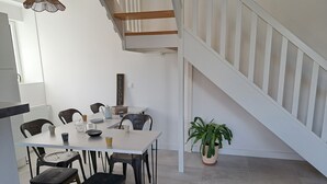 Un comedor con una mesa, sillas, una planta en maceta y una escalera.