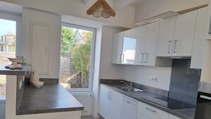 Una cocina moderna con armarios blancos, encimera negra, horno empotrado y ventana con vistas al verdor.