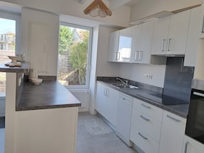 A modern kitchen with white cabinets, a black countertop, a built-in oven, and a window with a view of greenery.