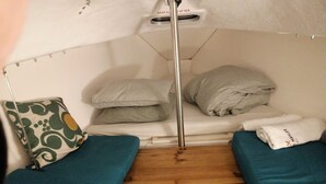 A small, enclosed sleeping area with a bunk bed, a single bed, a headboard, and a wooden floor.
