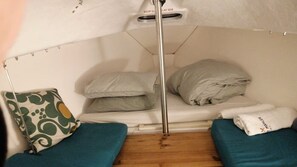 A small, enclosed sleeping area with a bunk bed, a single bed, a headboard, and a wooden floor.