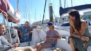 A group of people on a boat with a view of other boats and buildings in the background.