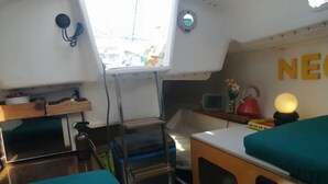 A compact cabin with a kitchenette, a small table, and a bed with teal bedding.