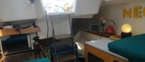 A compact cabin with a kitchenette, a small table, and a bed with teal bedding.