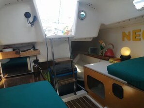 A compact cabin with a kitchenette, a small table, and a bed with teal bedding.