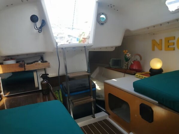 A compact cabin with a kitchenette, a small table, and a bed with teal bedding.