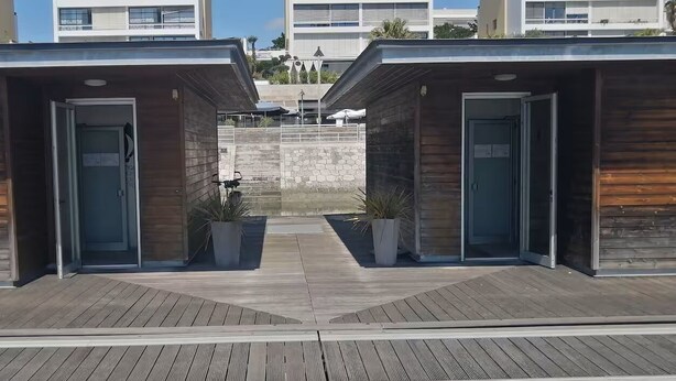 A modern building with two wooden doorways and potted plants.