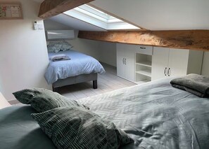 Une chambre avec un puits de lumière, un lit, une armoire et un banc intégré.
